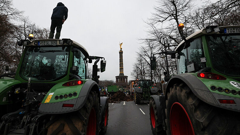 Тракторите са паркирани край пътя близо до Бранденбургската врата  На плакатите
