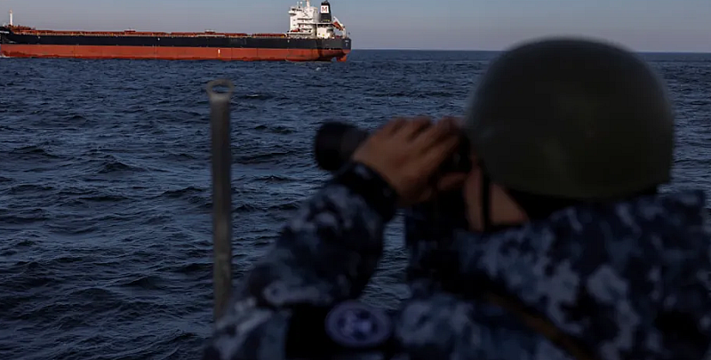 Войник от украинската брегова охрана наблюдава товарен кораб от патрулна